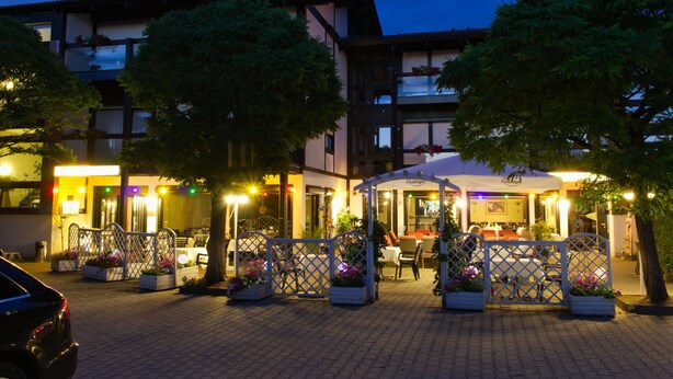 Un restaurante con terraza al aire libre, un porche cubierto y un coche estacionado cerca.