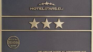 Eine Metallplakette mit dem Text HOTELSTARS.EU, drei Sternen und dem Logo der DEUTSCHE HOTELKLASSIFIZIERUNG.