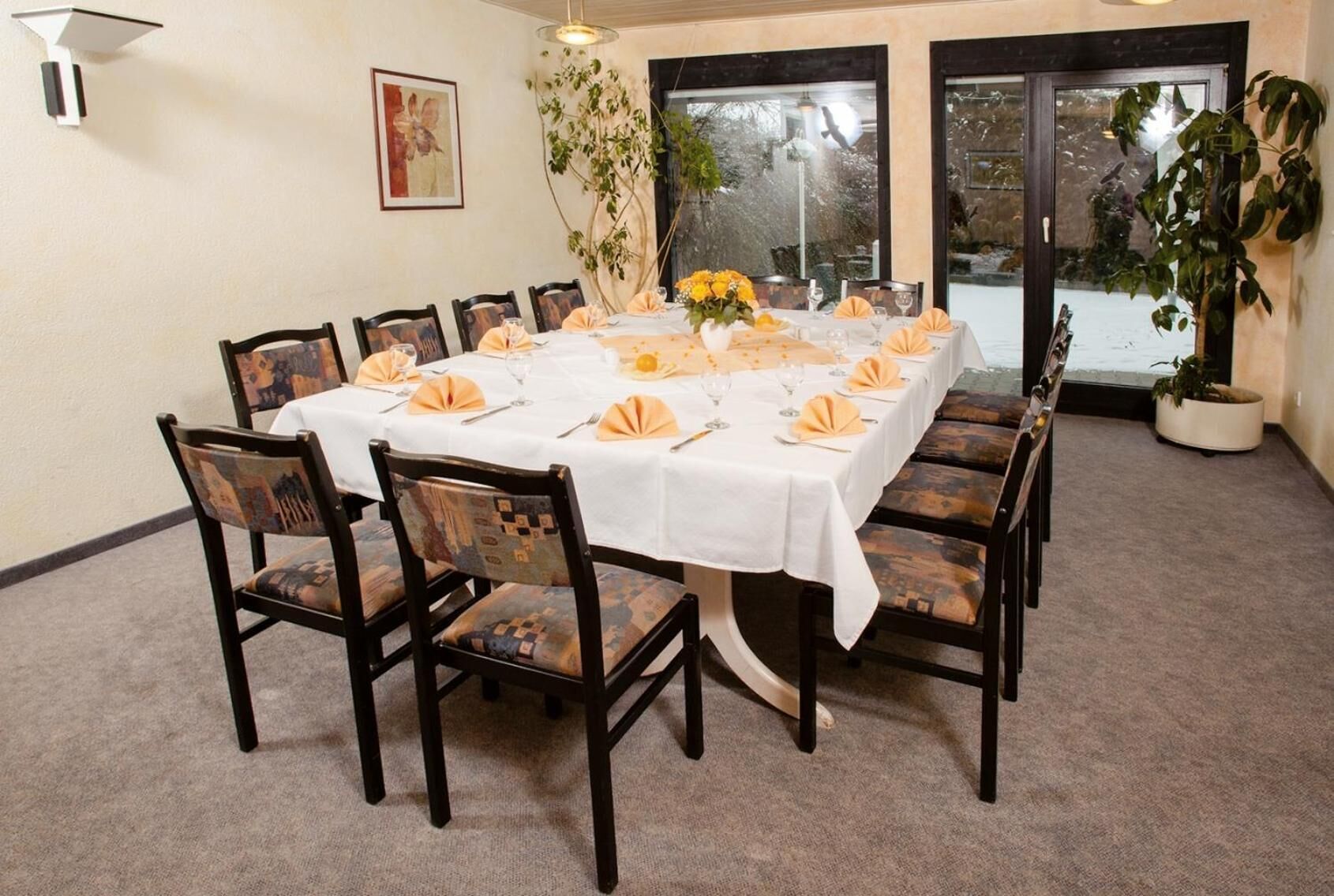 Une salle de conférence avec une table ronde, des chaises et une nappe blanche.