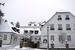 A snow-covered building with a white facade, multiple windows, and a traditional architectural style.