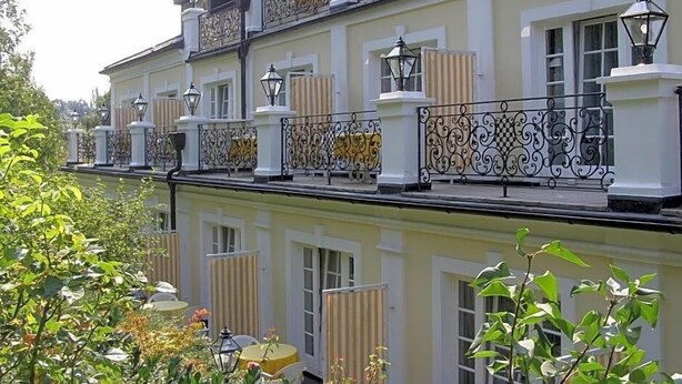 Un edificio de varios pisos con balcones, ventanas y asientos al aire libre.