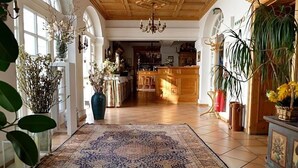 Un pasillo amplio con un tapete estampado, armarios de madera y plantas en macetas.