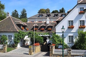 A traditional European-style building with a white facade, multiple windows, and a stone entrance.