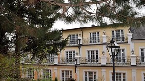 Un edificio de dos pisos con un balcón, un farol y un jardín.