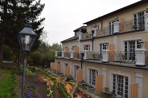 Ein mehrgeschossiges Gebäude mit Balkonen, Sitzgelegenheiten im Freien und einem Garten mit verschiedenen Blumen.