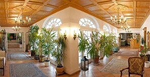 Ein großzügiger Innenraum mit hohen Decken, großen Fenstern und mehreren Zimmerpflanzen.