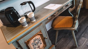 A small kitchenette with a coffee maker, two cups, and a kettle on a wooden table. - Post, ZUR (Bonn)