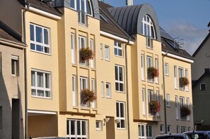 A multi-story building with balconies adorned with flower baskets. - Post, ZUR (Bonn)