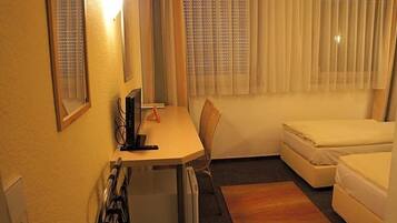Ein kleiner, kompakter Raum mit Schreibtisch, Stuhl und einem Bett.