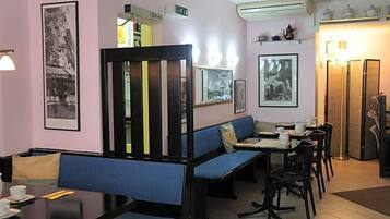 Ein Restaurant mit blauen Sitzkissen, einer schwarzen Trennwand und gerahmten Bildern an den Wänden.