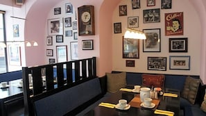 A dining area with tables, chairs, and a wall adorned with framed pictures.