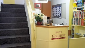 A hotel reception desk with a staircase leading to the upper floor.