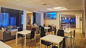 Un moderno vestíbulo de hotel con un área de descanso, una gran pantalla de televisión y una mesa de billar al fondo.