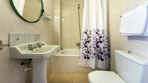 Un baño con lavabo, inodoro, bañera y cortina de ducha.