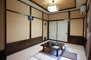Una habitación japonesa tradicional con suelo de tatami, una mesa baja con una bandeja y puertas correderas.