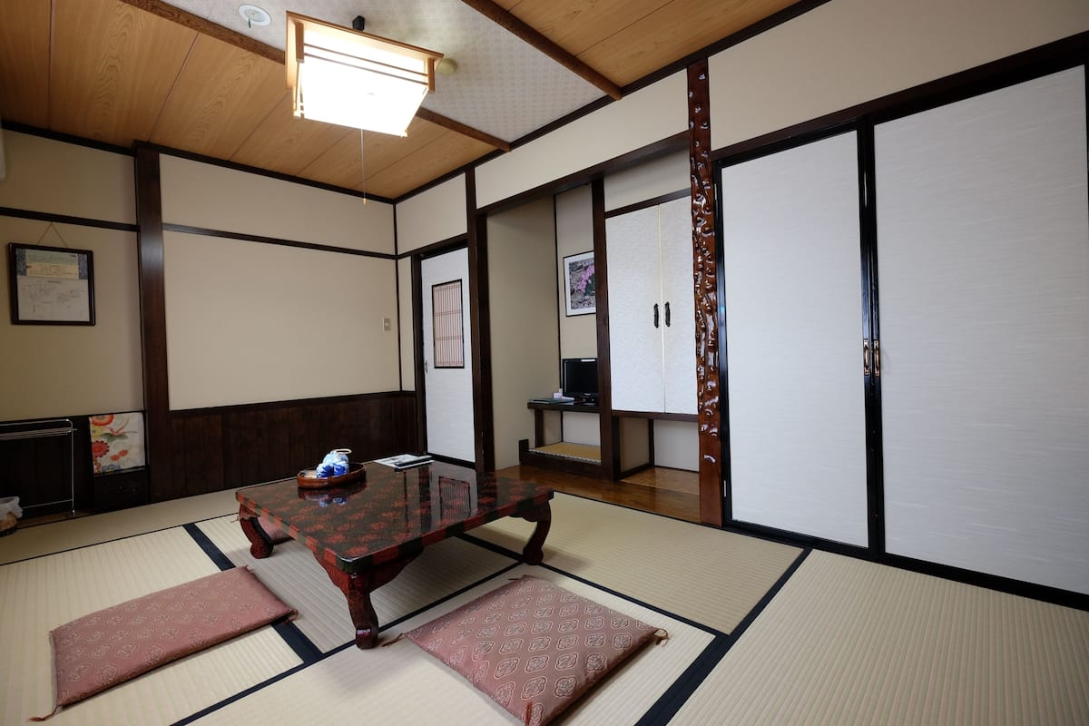 Une pièce de style japonais traditionnel, avec un sol recouvert de tatamis, une petite table en bois et des portes coulissantes.