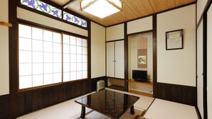 A traditional Japanese room with tatami flooring, a low table, sliding doors, and a large window with a floral design. - Ryoso Tsuyukusa (Takayama)