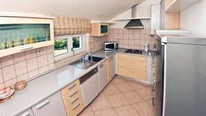 A modern kitchen with a stainless steel sink, a microwave, a stove, and a refrigerator. - Villa Molina (Zupa dubrovacka)