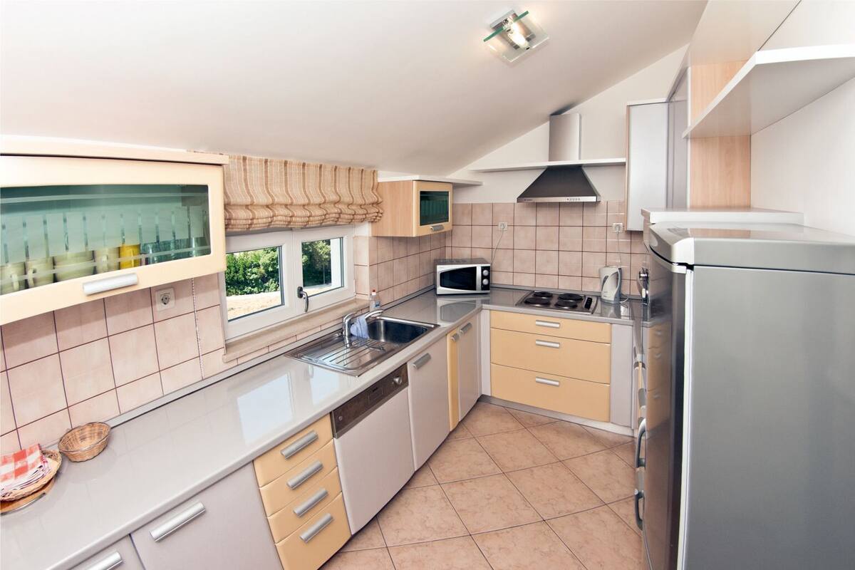 A modern kitchen with a stainless steel sink, a microwave, a stove, and a refrigerator.