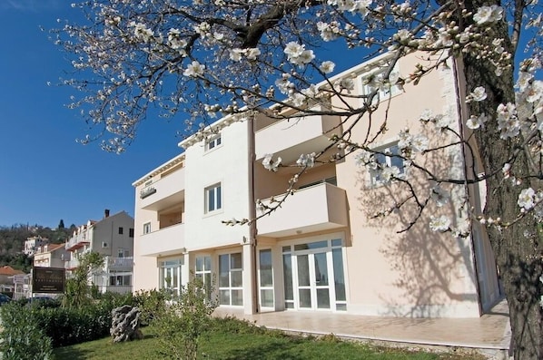 A multi-story building with balconies, large windows, and a clear sky.