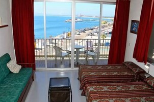 A room with a balcony overlooking a beach and sea.