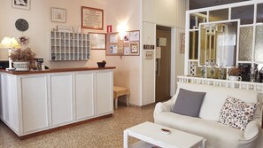 A reception area with a white reception desk, a sofa, and a coffee table. There are framed pictures on the wall, a bulletin board, and a sign that says "Welcome". - Maeva (Lloret de Mar)