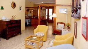 A cozy living room with a wooden dresser, a yellow armchair, a glass coffee table, and a blue sofa. - Maeva (Lloret de Mar)