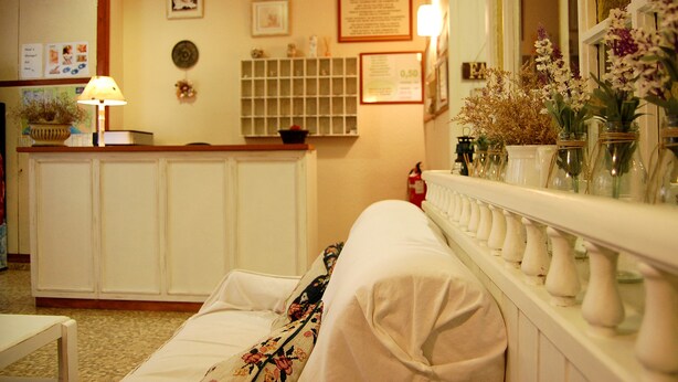 A hotel room with a bed, a nightstand, a lamp, a bulletin board, and a shelf with decorative items. - Maeva (Lloret de Mar)
