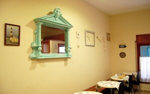 A room with a mirror, a framed picture, a small table with a tablecloth, and a sign on the wall. - Maeva (Lloret de Mar)