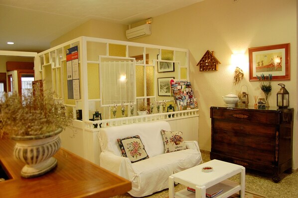 A living room with a white sofa, a wooden dresser, a white coffee table, and a decorative plant. - Maeva (Lloret de Mar)