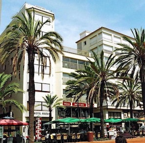 A hotel with a white facade, palm trees, outdoor seating, and a sign for 'Marcs.' - Maeva (Lloret de Mar)