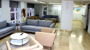 Een moderne hotellobby met banken, een salontafel en een receptiebalie.