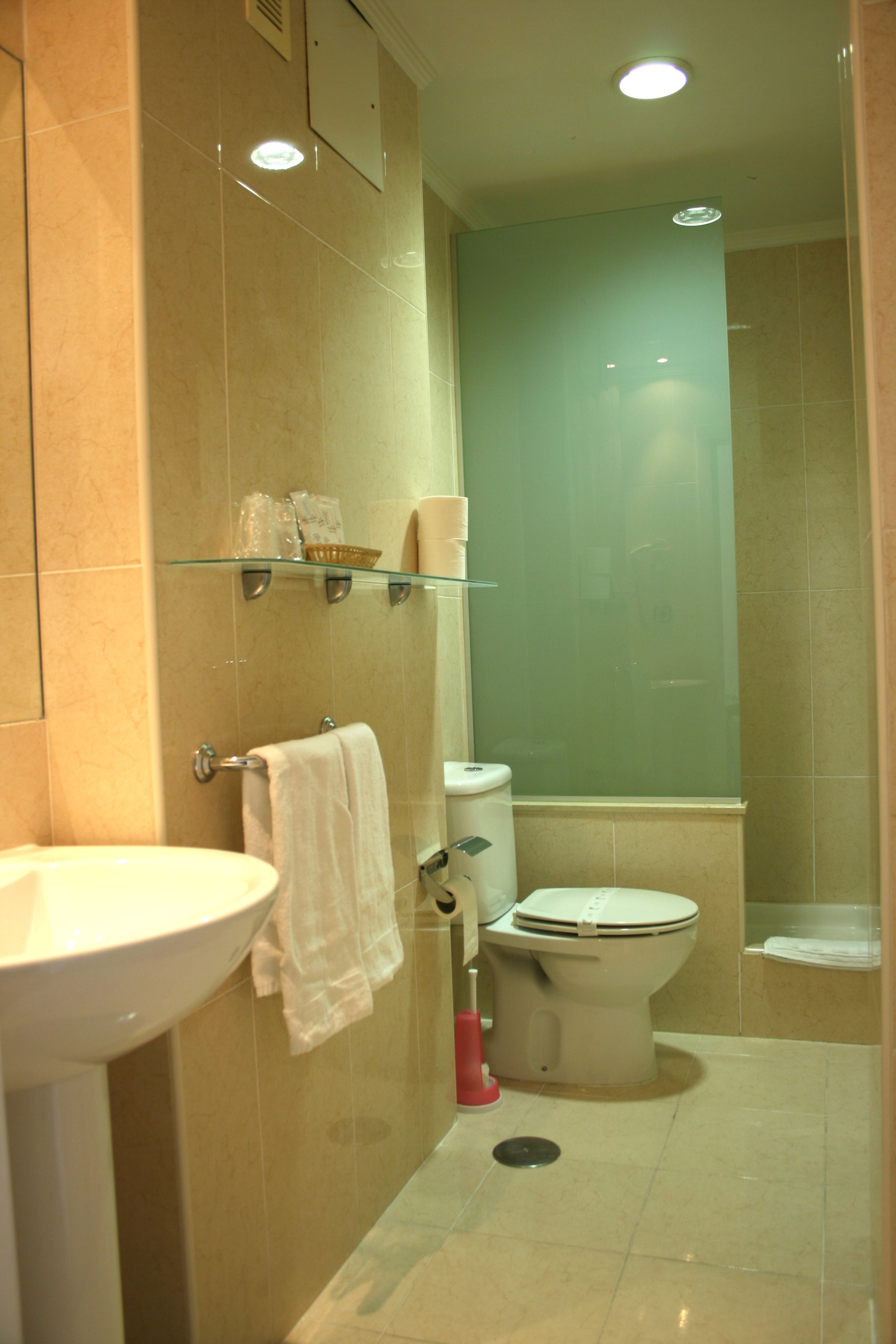 Un baño con lavabo, inodoro y estantes de vidrio.