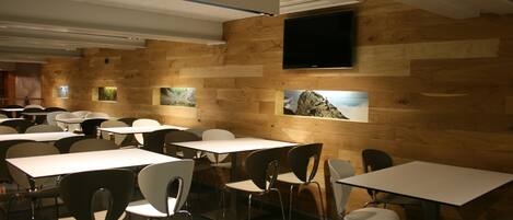 A modern dining area with wooden walls, white tables, and metal chairs.