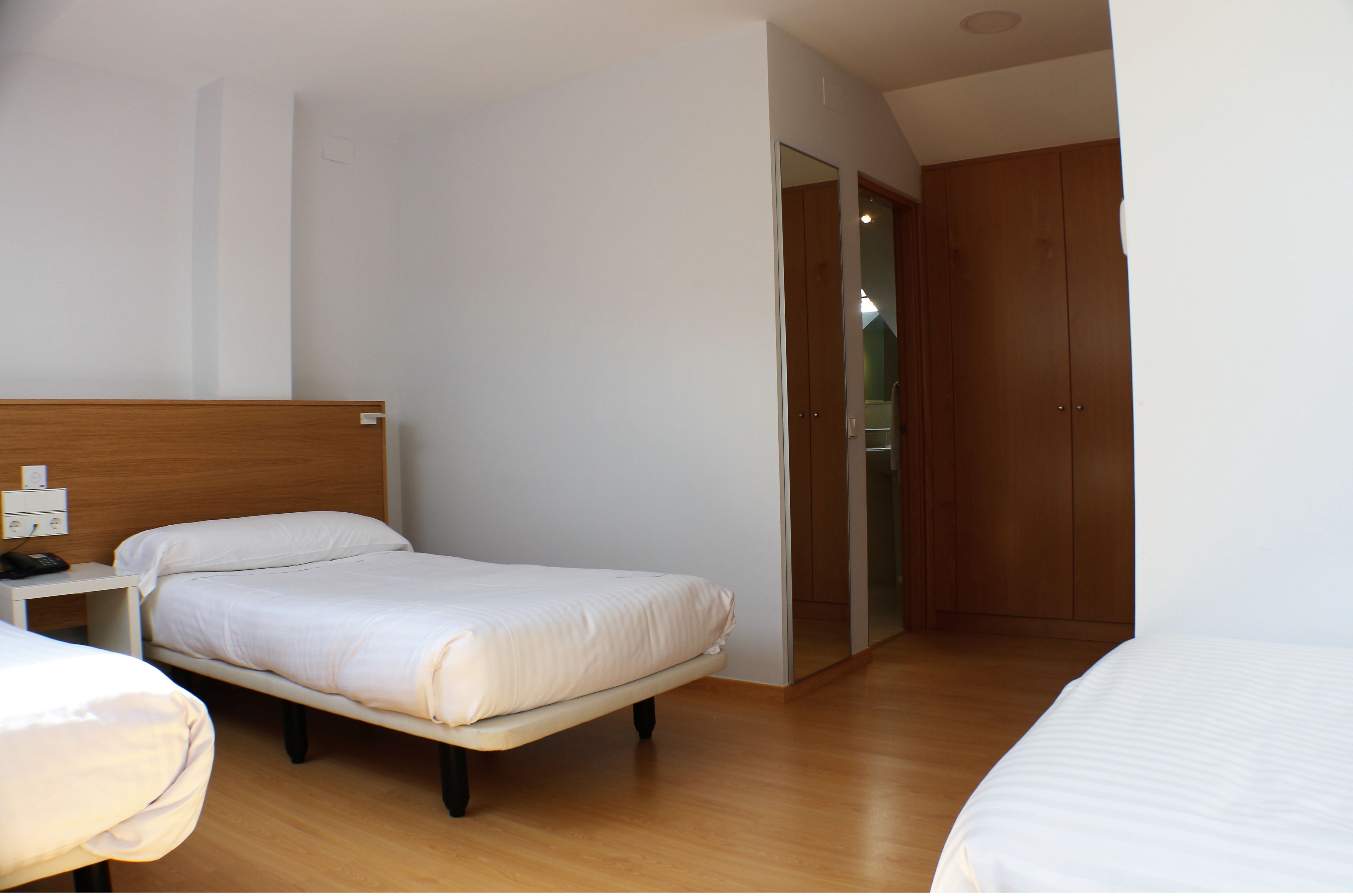 Una habitación de hotel con una cama individual, una mesita de noche y un armario.