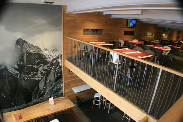 A restaurant with a high wooden ceiling, a large mural of a mountain, and multiple tables and chairs. - Hotel Picos de Europa (Santander)