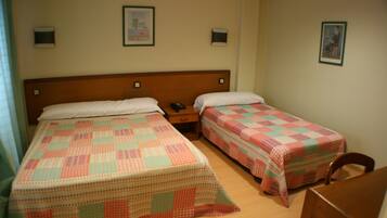 Una habitación de hotel con dos camas individuales, cabeceros de madera, mesitas de noche y una silla de madera.