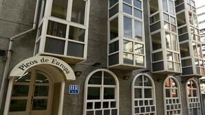 Een gebouw met meerdere ramen en balkons, een bord met de tekst 'Picos de Europa' en een blauw 'HR'-bord.