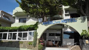 The exterior of the Ansel Hotel with a prominent entrance, steps leading up to the door, and a bar area visible on the left side. - Anseli Hotel Apartments and Studios (Rhodes)