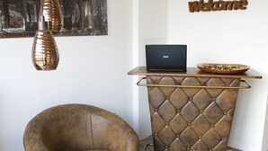 A room with a leather armchair, a round table with a mirror, a laptop on a wooden shelf, and a 'Welcome' sign on the wall. - Hotel Central Wesseling (Wesseling)