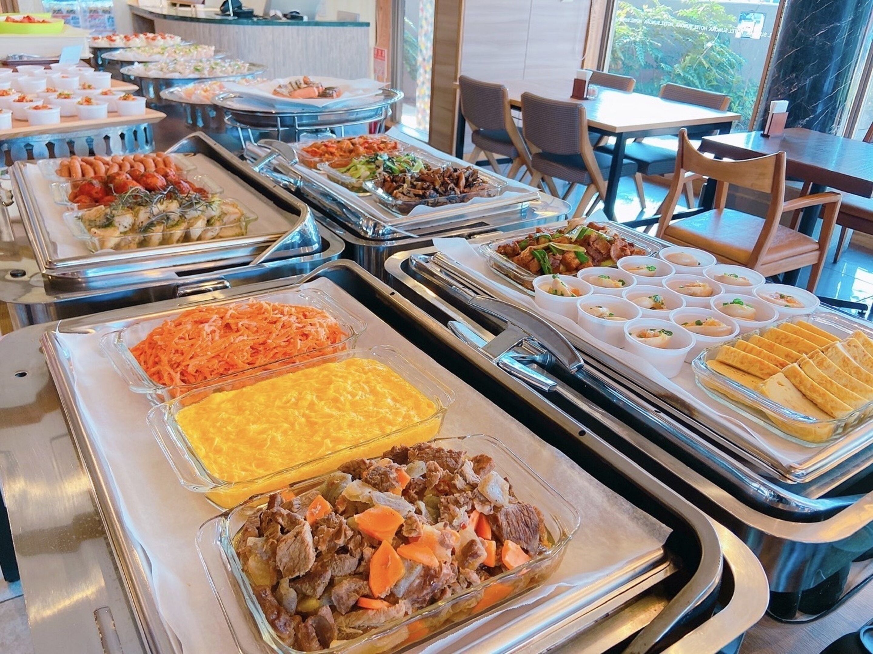 A buffet with various dishes including meat, vegetables, and desserts.