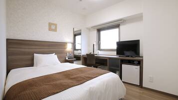 A hotel room with a bed, a desk, a television, and a refrigerator.