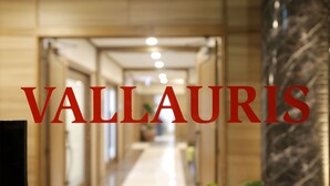 Un pasillo de hotel con pared de mármol y una planta. Se exhibe claramente el texto "VALLAURIS".