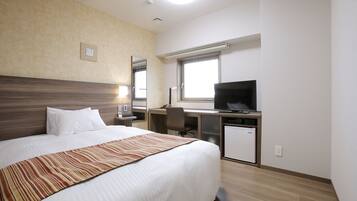 Habitació d'hotel amb un llit gran, una taula de treball amb un ordinador i una televisió.