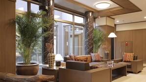 Un hall amplio con zona de estar, ventanas grandes y plantas en macetas.