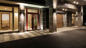 Una entrada de hotel moderna con suelo de cuadros, puerta de madera y planta en maceta.