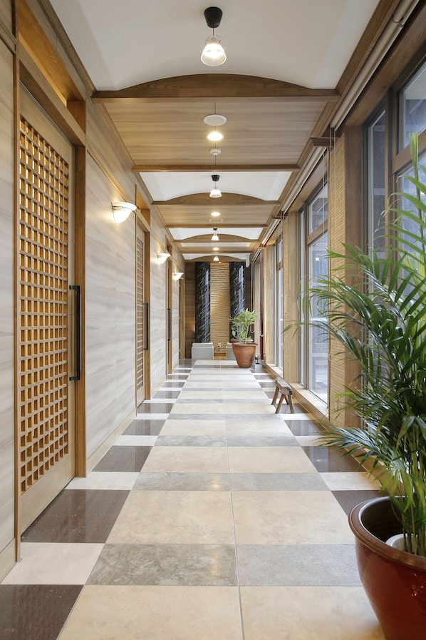 A hallway with a checkered floor, wooden paneling, and potted plants.