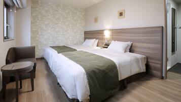 Ein Hotelzimmer mit zwei Betten, einem kleinen runden Tisch, einer Couch und einer Wand mit Muster.