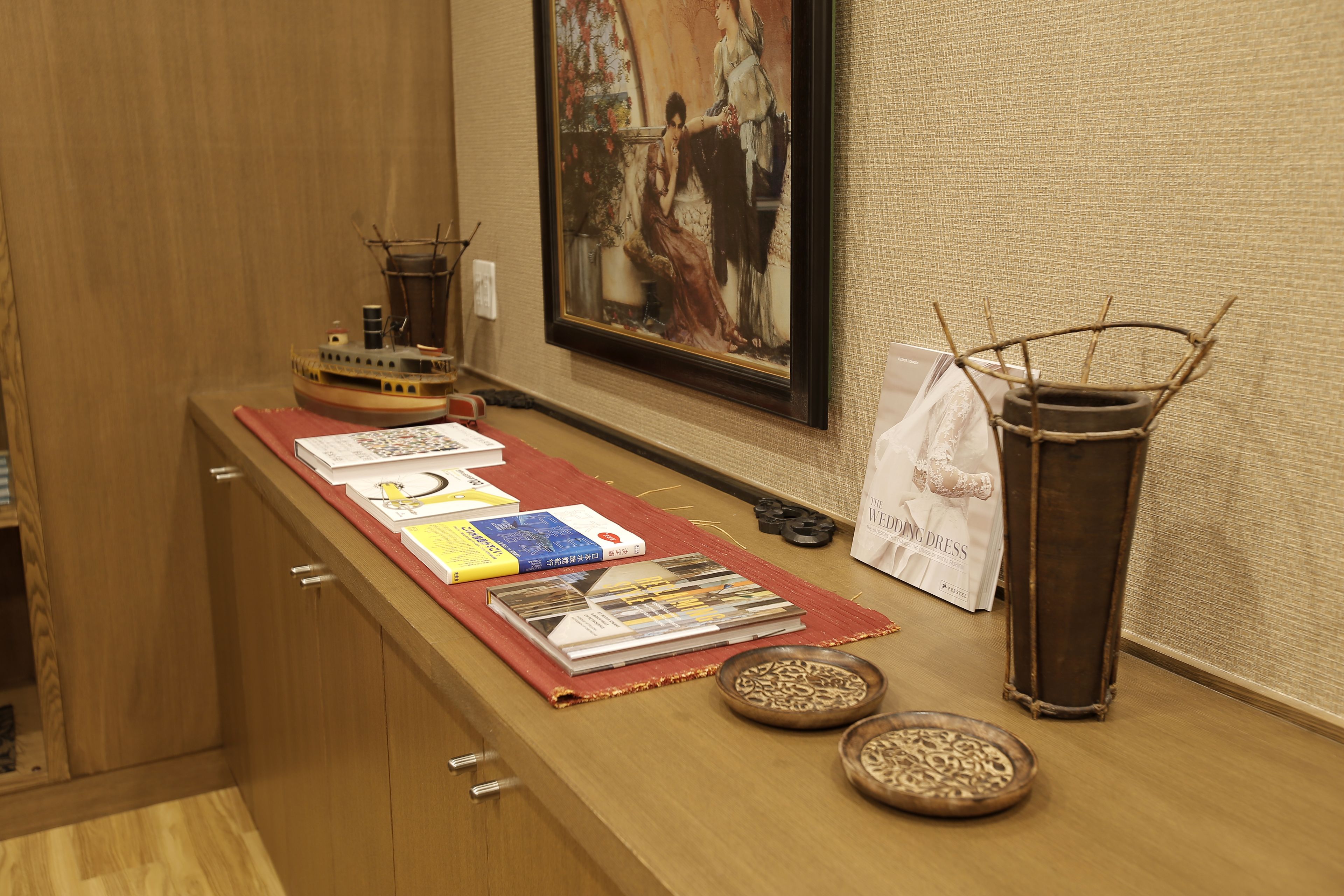 Una encimera de madera con revistas, un modelo de barco pequeño y un jarrón decorativo.