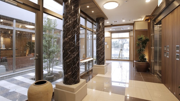 Un vestíbulo amplio con columnas de mármol, un jarrón grande y una planta en maceta.